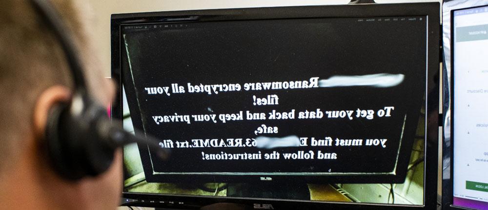  A man reads a ransomeware message on his computer monitor.